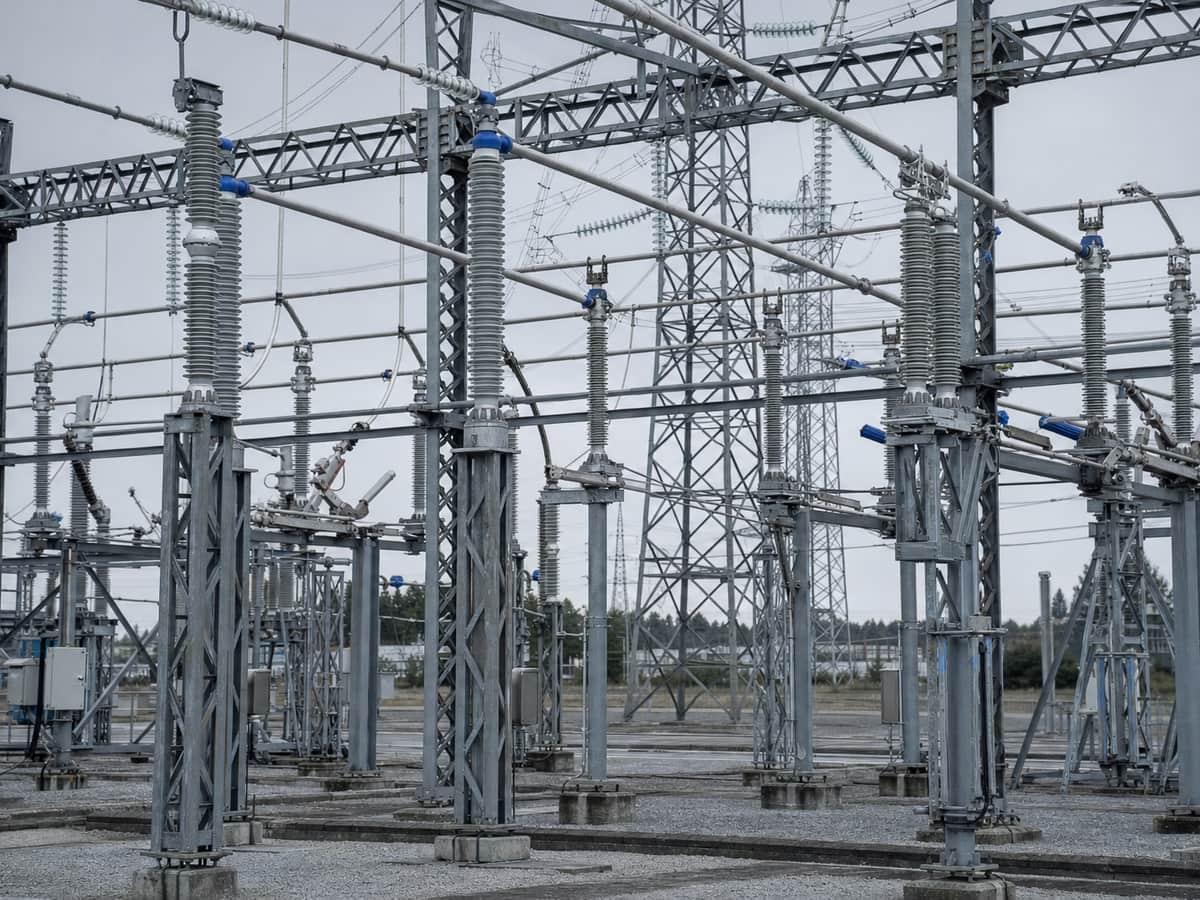 High-voltage substation gantries carrying strings of insulators against a pale overcast sky