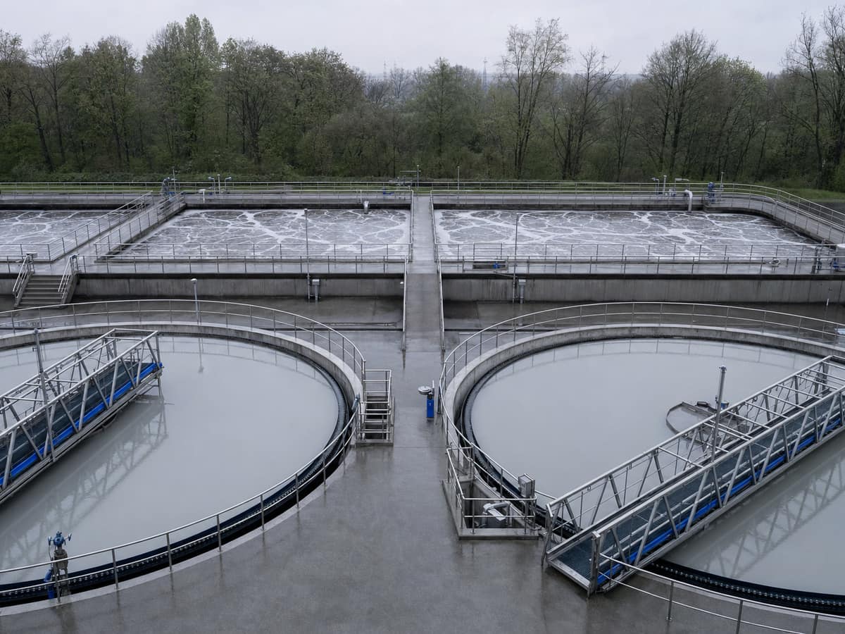 Circular concrete clarifier tanks and steel walkways at a modern wastewater treatment works