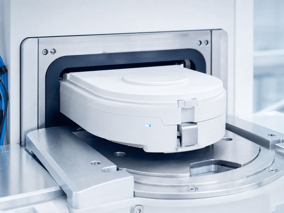 Wafer carrier pod docked at a tool in a bright cleanroom